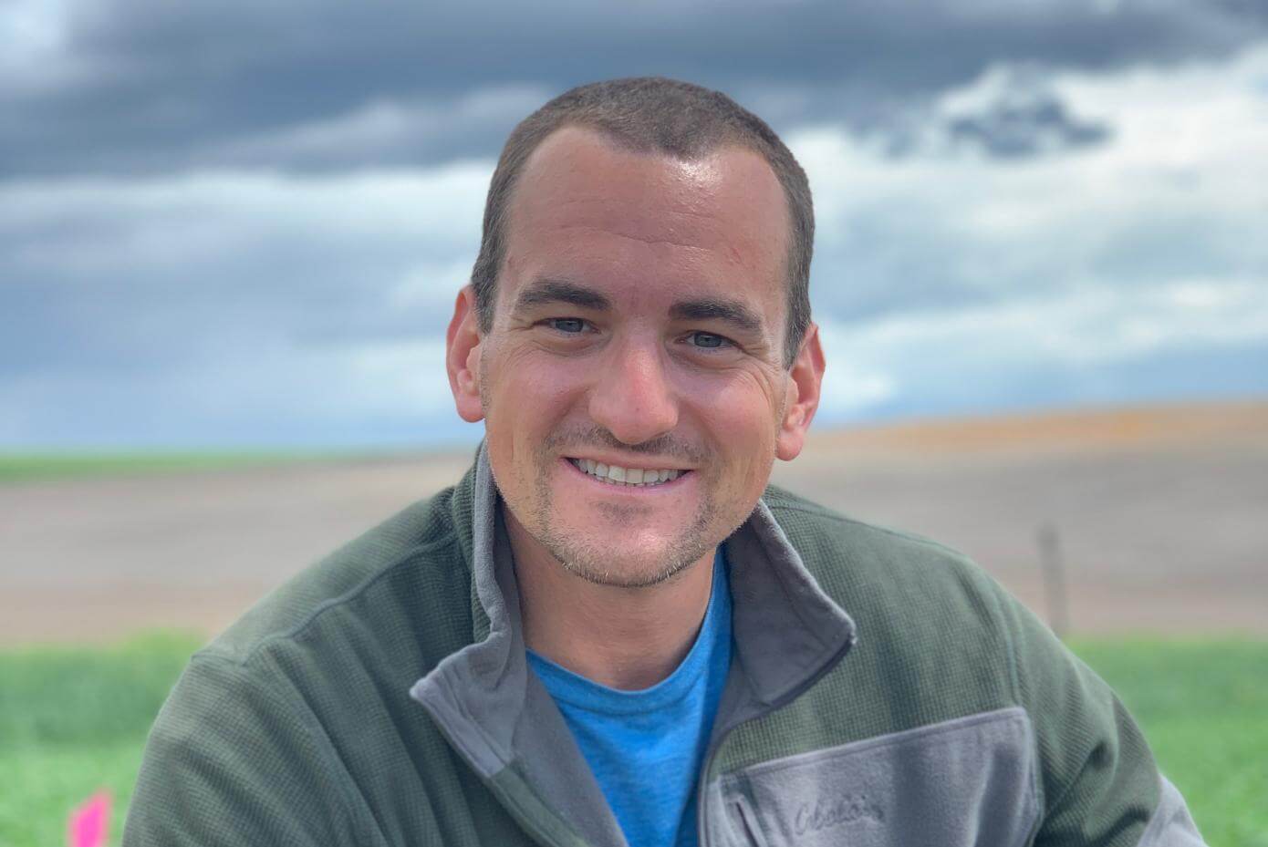 A man smiling with a field in the background.
